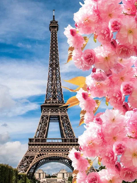 A close-up of the Eiffel Tower framed by vibrant pink cherry blossoms against a blue sky.