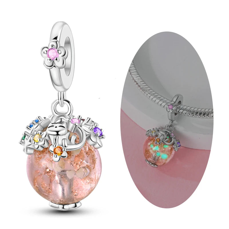 A silver heart charm bead with pink zircon and a floral dangle earring shown against a pink background.