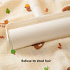 A white baby gauze swaddle blanket is shown open on a light fabric with small animal print, demonstrating a refuse to shed ha