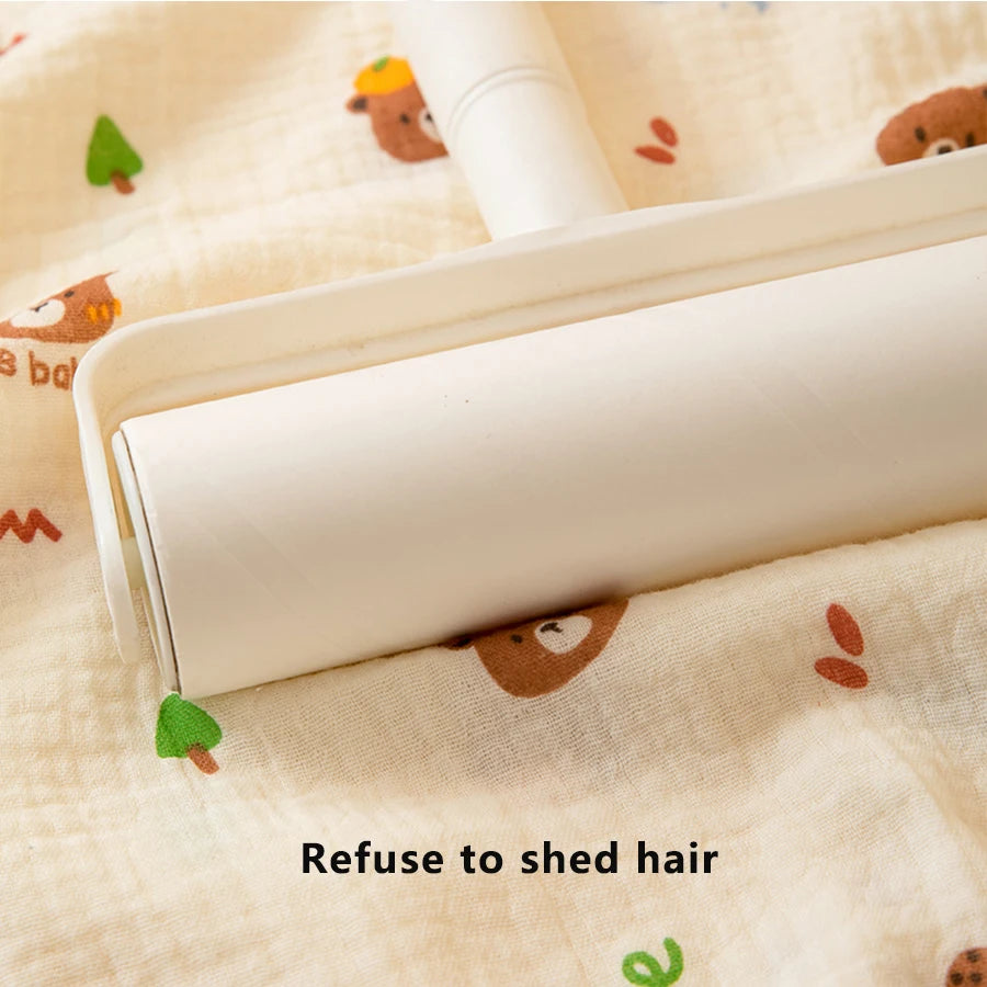 A white baby gauze swaddle blanket is shown open on a light fabric with small animal print, demonstrating a refuse to shed ha