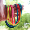 A hand holds a bundle of colorful rainbow elastic jump ropes, including red, orange, yellow, green, and blue.