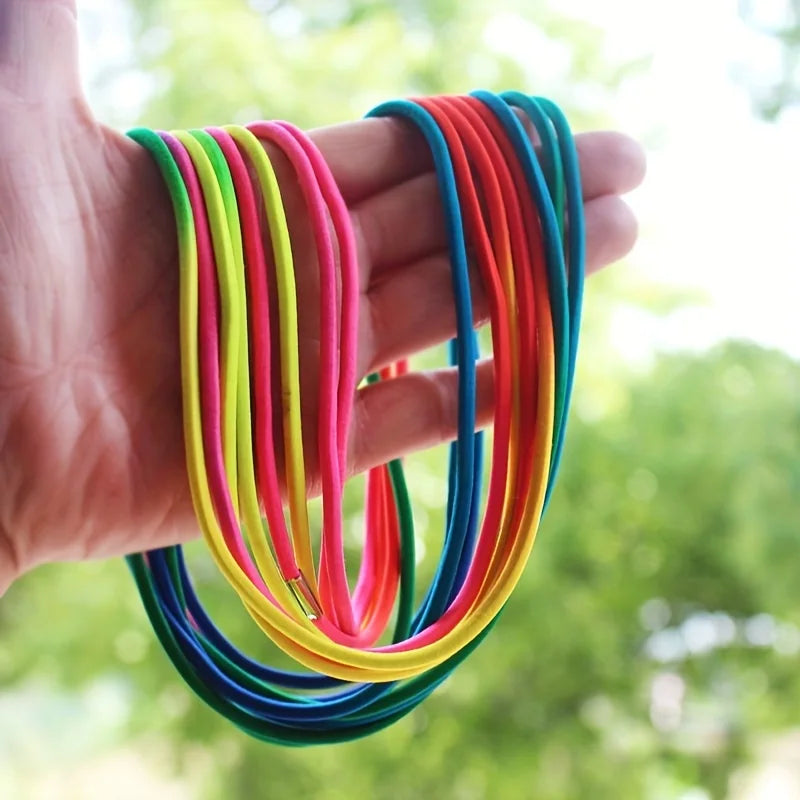 A hand holds a bundle of colorful rainbow elastic jump ropes, including red, orange, yellow, green, and blue.