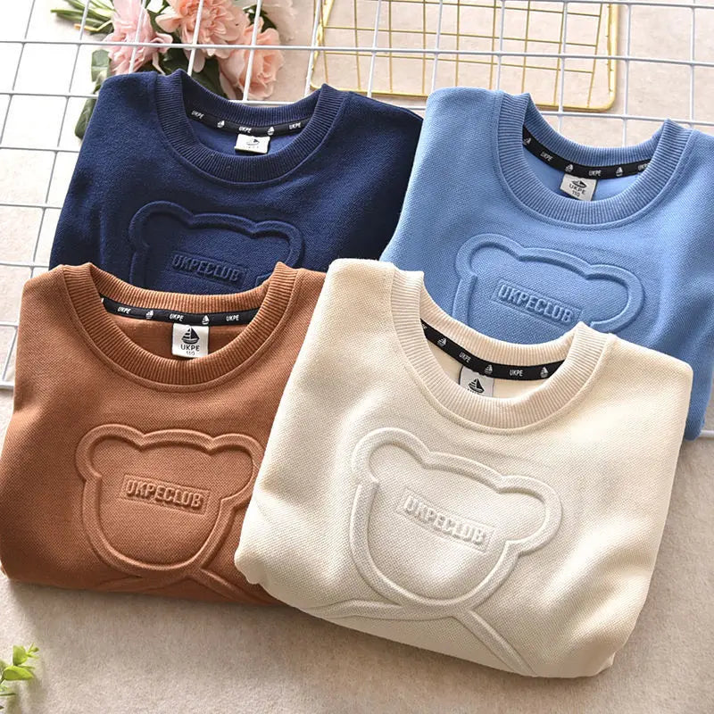 Three baby blue, navy, and beige cartoon bear pullover sweatshirts displayed on a light surface.