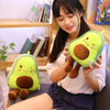 A young woman holds a bright green avocado plush toy with brown accents.
