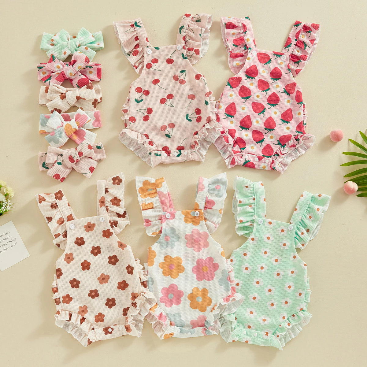 A set of pink and green baby girls summer rompers with matching floral patterns and ruffled details.