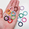 A hand holds various colorful alloy snap hook keychain clips in different colors and sizes.
