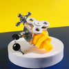 A wooden Montessori busy cube toy with silver and yellow components displayed on a white circular base.