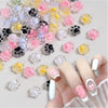 A hand displays a variety of luminous cat paw nail art charms for DIY crafts.