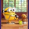 A yellow Minions collectible figure wearing goggles sitting next to a small brown bear figure.