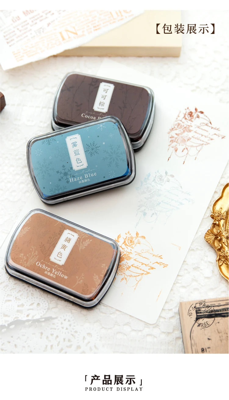 Display of three vintage craft oil-based ink pads in dark glass containers, showing shades of blue, yellow, and brown.