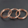 Three coils of solid bare copper wire demonstrating a twisted coil pattern.