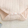 A light pink knitted baby romper and pants set with a gathered front detail.