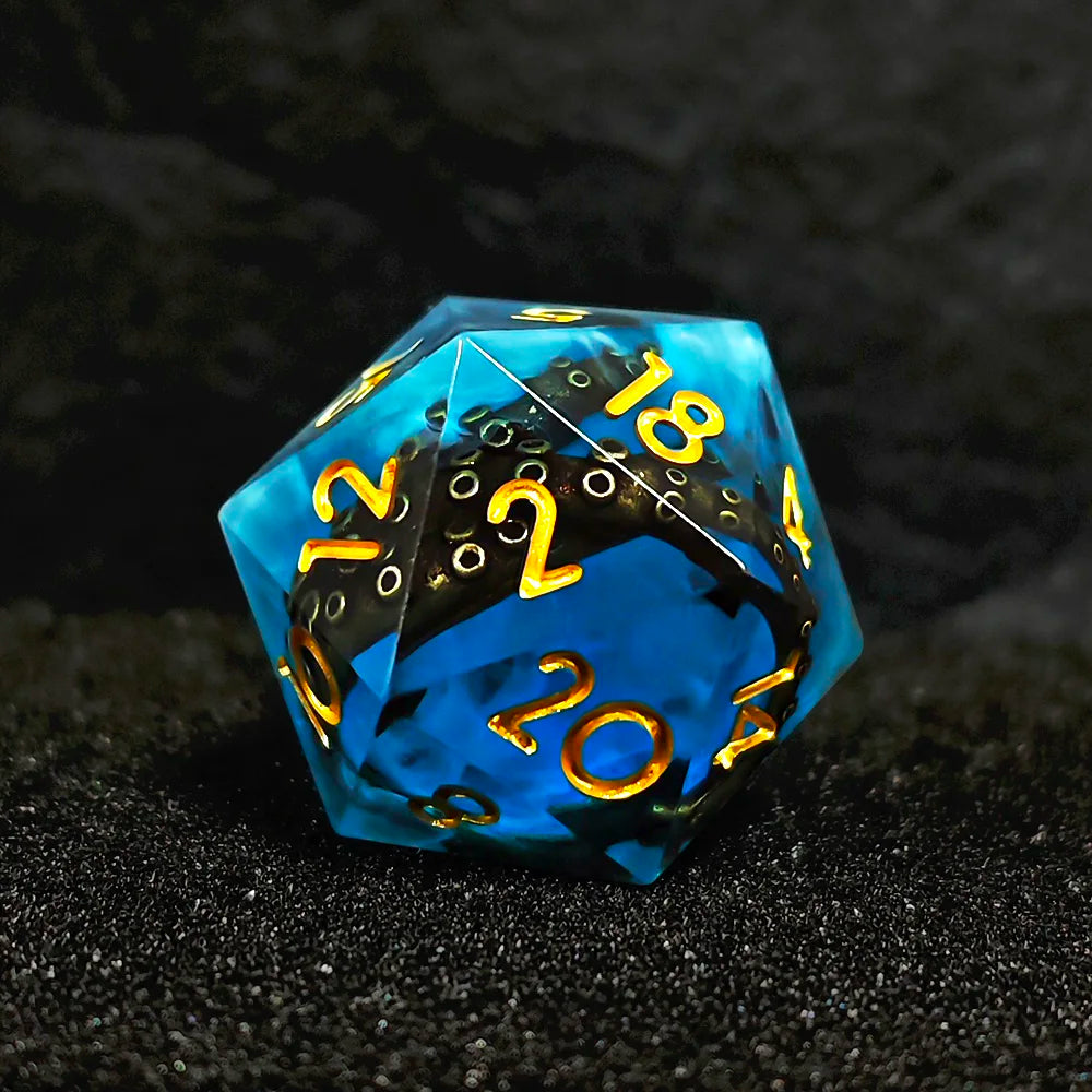 A translucent blue resin die with numbers on its faces resting on a dark surface.
