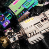A close-up of an alloy shell-ejecting toy pistol and fidget spinner set with iridescent green and silver components.
