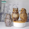 A realistic owl garden statue bird deterrent decor made of textured ceramic sits on a white wooden base.