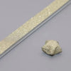 A close-up view of glitter origami star paper strips lying on a gray surface.