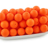 A pile of small, round, orange silicone beads for jewelry making and DIY crafts.