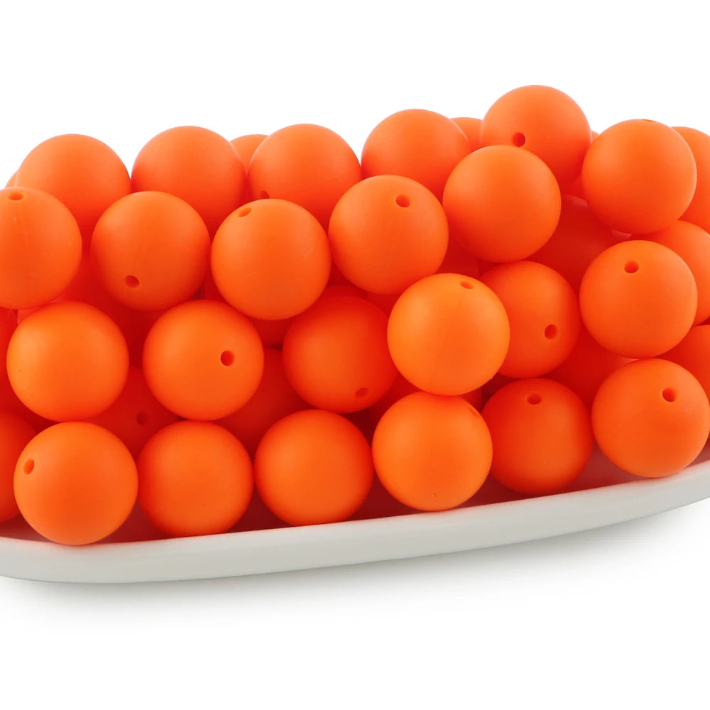 A pile of small, round, orange silicone beads for jewelry making and DIY crafts.