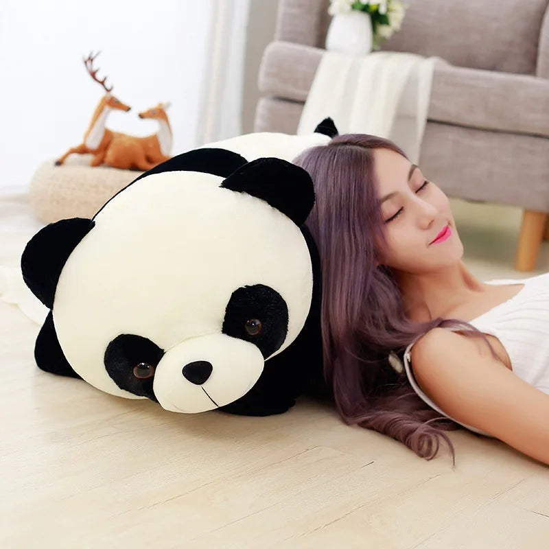 A woman is relaxing on the floor with an adorable black and white panda plush pillow.