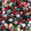 A close-up view of a vibrant mix of colorful glass beads including reds, greens, pinks, and clear stones for jewelry making