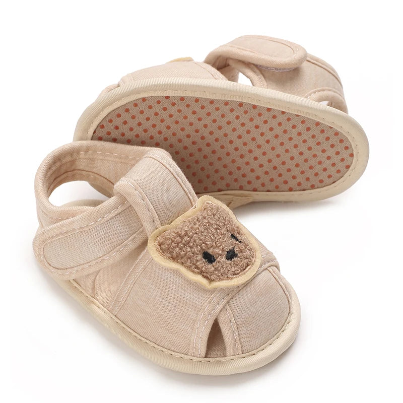 A pair of beige soft cotton baby walking shoes with anti-slip soles and suede toe caps.