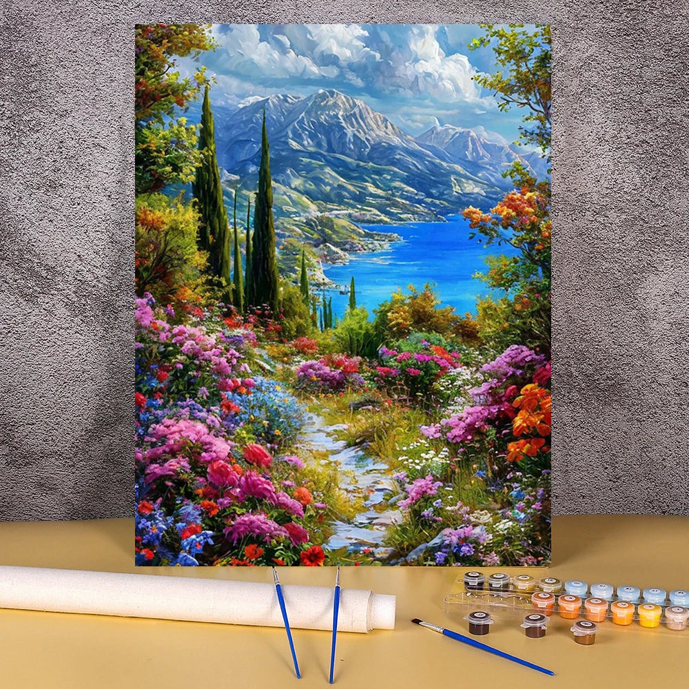 A painting in progress featuring a vibrant landscape with mountains, blue water, and colorful flowers.