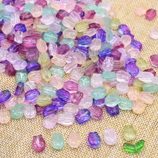 A pile of iridescent glass beads in various shades of pink, purple, green, and yellow scattered on a beige fabric.