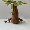 A brown plush toy resembling a mandrake with green leaves growing from its head.