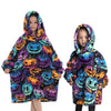 A young girl wearing a colorful Halloween-themed flannel hoodie sweater with pumpkin and spooky designs.