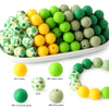 A collection of soft food-grade silicone beads in various shades of green and yellow.