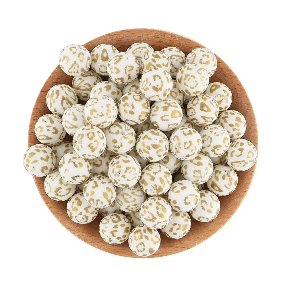 A wooden bowl filled with small, round, white silicone beads speckled with gold or tan dots.