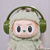 Labubu doll wearing a green fuzzy hoodie and headphones.
