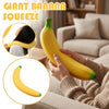Hands squeezing a yellow giant banana squishy toy in a living room setting.