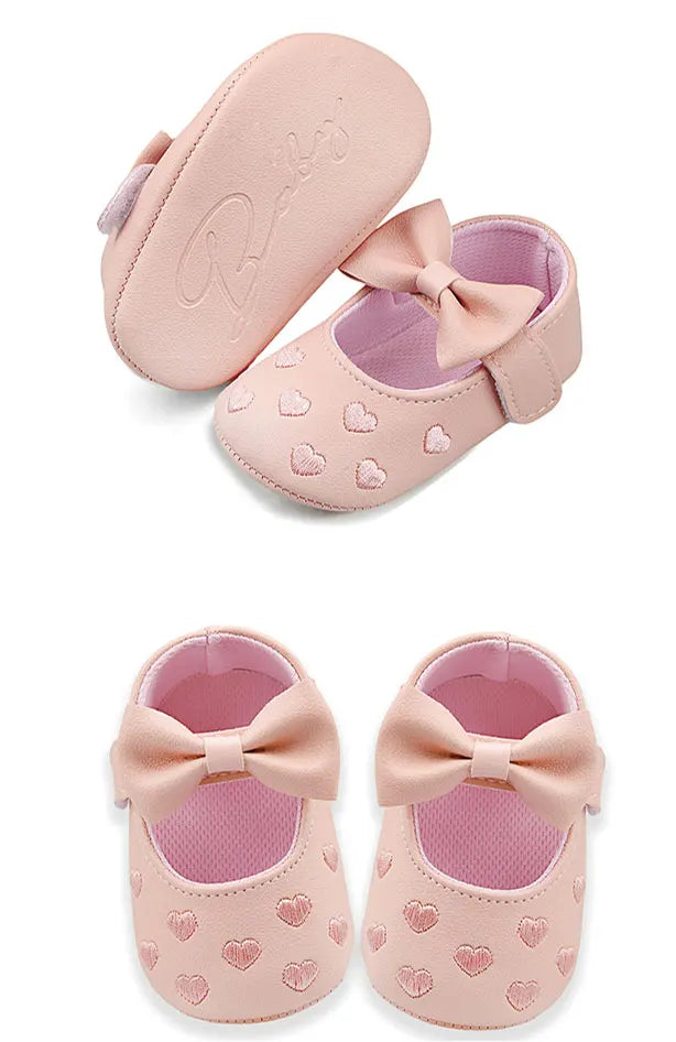 A pair of pink baby girl bow-knot first walker shoes with soft anti-slip soles.