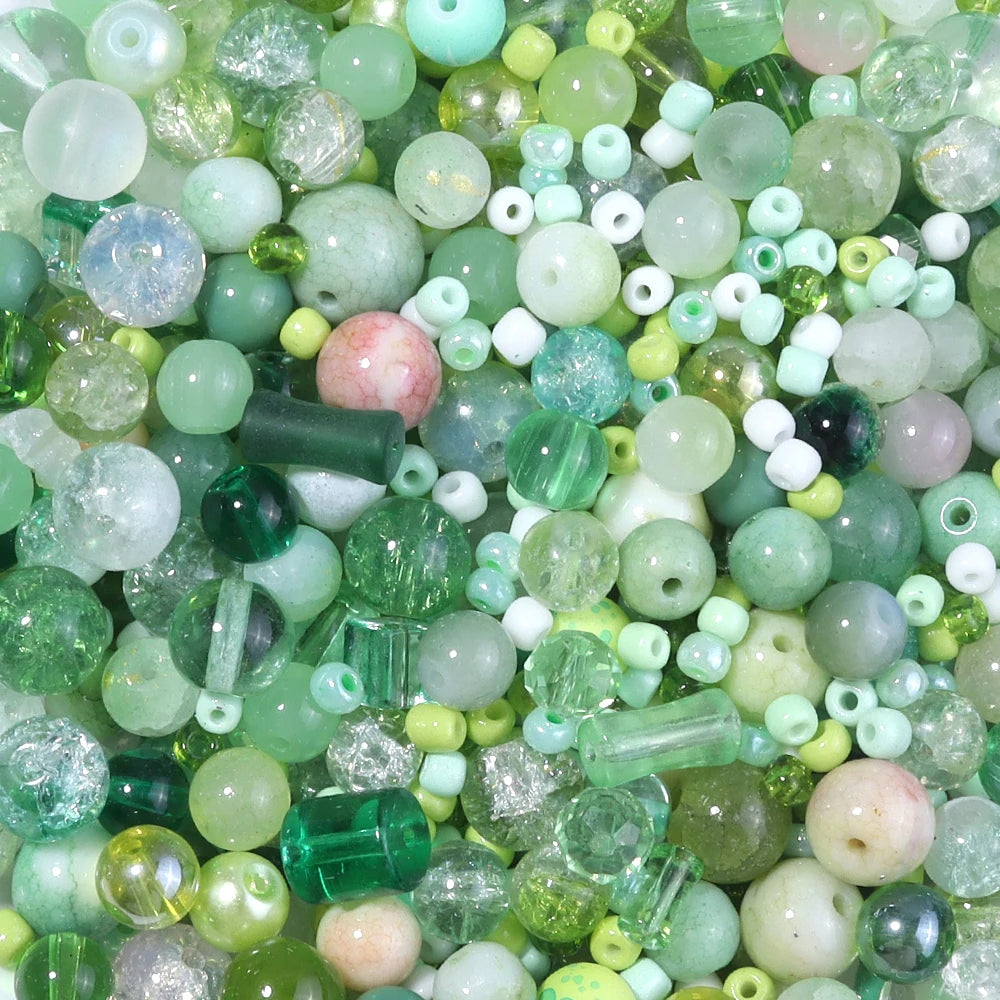A close-up view of a vibrant mix of green, pink, and white glass beads for DIY jewelry making