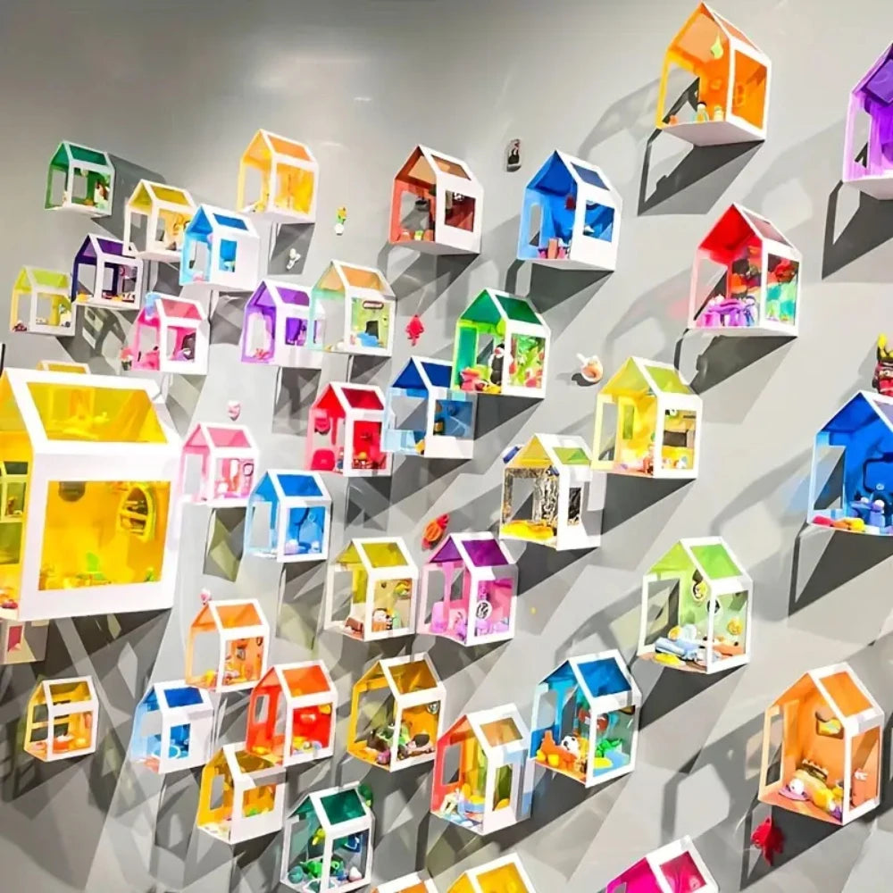 A collection of colorful, transparent PVC sheet houses and models displayed on a gray wall.