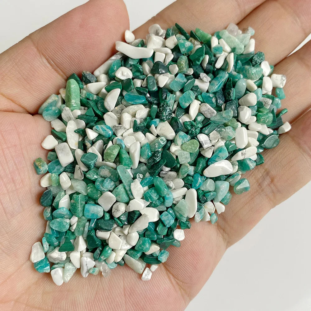 A handful of natural tumbled stone chips featuring shades of green and white crystals.