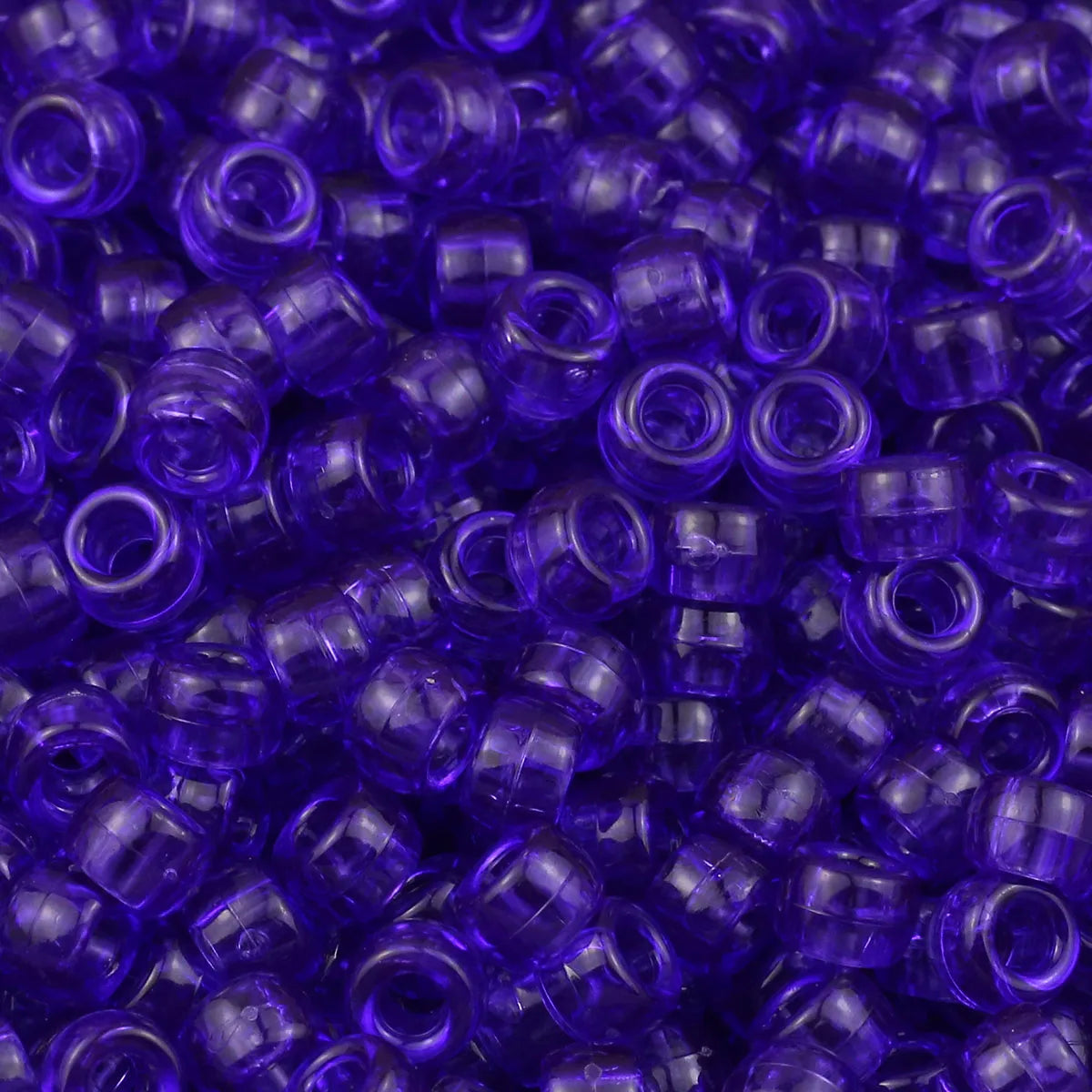 A close-up view of small, translucent purple pony beads for jewelry making and crafts.