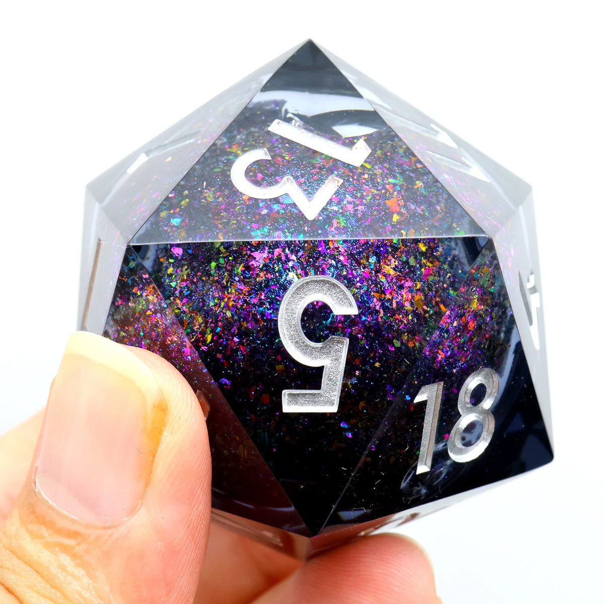 A hand holds a translucent resin D20 die with large numbers 13, 5, and 18 showing colorful liquid swirls.