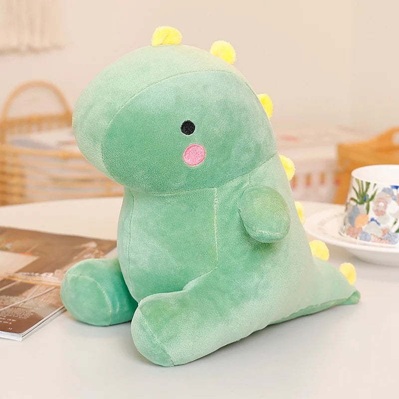 A soft green dinosaur plush toy with yellow spikes sitting on a white table.