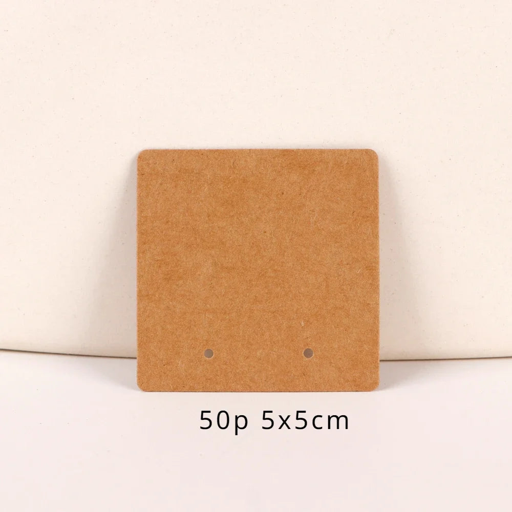 A square brown kraft jewelry display card with two small holes, measuring 5x5 cm.