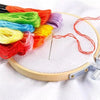 A collection of vibrant colored embroidery floss on a wooden hoop with a needle for cross stitch and crafts