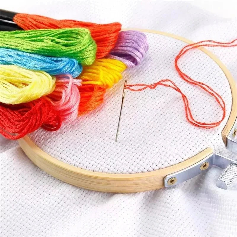 A collection of vibrant colored embroidery floss on a wooden hoop with a needle for cross stitch and crafts
