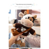 A brown and white cow plush toy with dark brown accents is being held by a person.