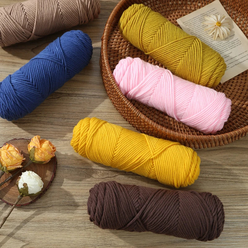 A collection of brightly colored yarn skeins, including yellow, pink, blue, and brown, displayed on a wooden surface.