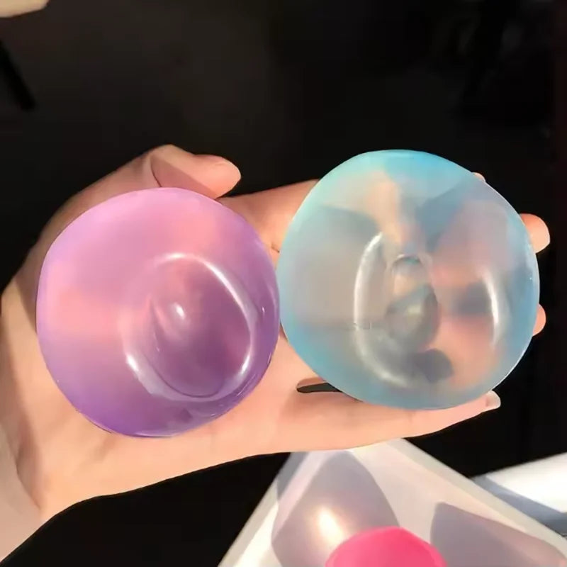 A hand holds two translucent silicone fidget balls, one purple and one light blue/teal.