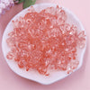 A pile of pink translucent acrylic bow beads for jewelry making on a white plate.