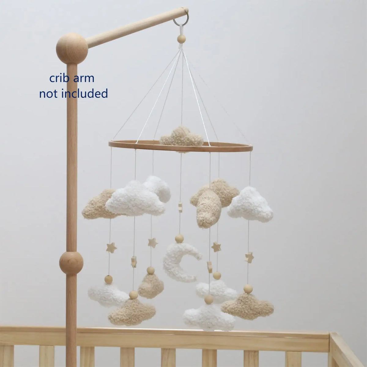 Handmade felt baby mobile featuring clouds and a moon suspended from a wooden crib arm.