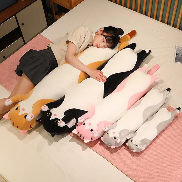 A person is lying on a bed surrounded by various funny cat plush toys in orange, white, and black.