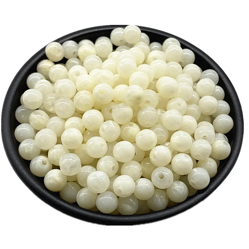 A pile of small, round, translucent white acrylic beads for jewelry making.